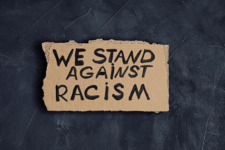 We stand against racism text on cardboard over dark background